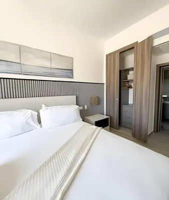 a bedroom with a large white bed and a window at Alojamientos en Coral Bay II Cerca del Hard Rock Hotel Punta Cana in Punta Cana
