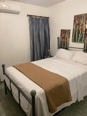a bedroom with a bed with white sheets and a window at Recidencial sharael house in San Isidro