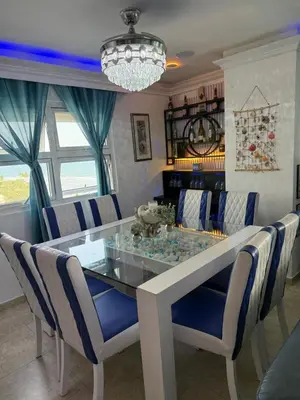 a dining room with a glass table and blue chairs at Beachfront Three Bedroom apt with Jacuzzi in Juan Pedro