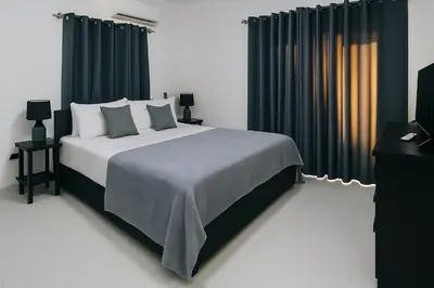 a bedroom with a large bed with black curtains at Modern Serviced Apartment with Free Wi-Fi, 24h Power & Private Parking in Sosúa