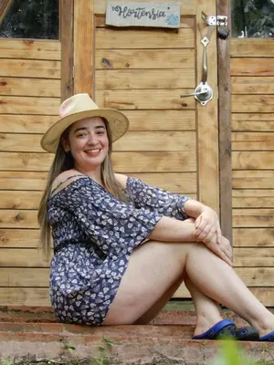 a woman wearing a hat sitting in front of a building at Eco Camping Jarabacoa in Jarabacoa