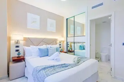 a bedroom with a large white bed with blue pillows at Comfy Retreat Balcony Grill Pool in Punta Cana