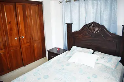 a bed with a wooden headboard in a bedroom at Best location Big 3 Bdrs, Fully Stocked and A/C in Santo Domingo
