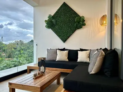 a living room with a black couch and a table at ALL-NEW Modern and Stylish Apartment with Rooftop Infinity Pool in Las Terrenas