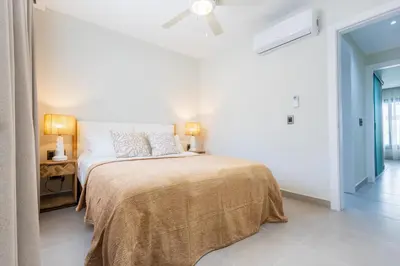 a white bedroom with a bed and a ceiling fan at Brand New 2BR Stylish Apartment in the Heart of Punta Cana, Gardenia Gated Community in Punta Cana