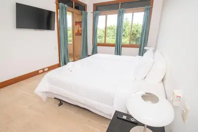 a bedroom with a white bed and a tv at Espectacular Apto en Casa de Campo Los Altos 3 in La Romana
