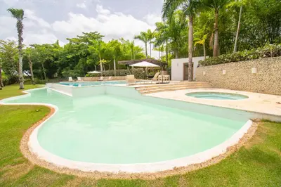 a large swimming pool in a yard with trees at Espectacular Apto en Casa de Campo Los Altos 3 in La Romana