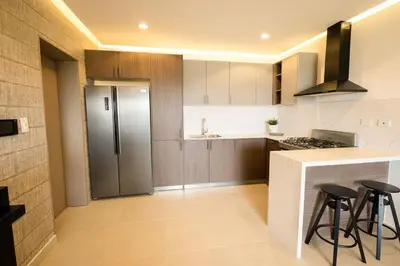 a kitchen with a refrigerator and some bar stools at Views, pool and gym, 2 BR family friendly in Santiago de los Caballeros
