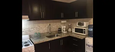 a kitchen with black cabinets and a sink and a microwave at Garden condos in Sosúa
