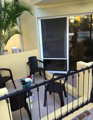 a balcony with chairs and a table and a window at Garden condos in Sosúa