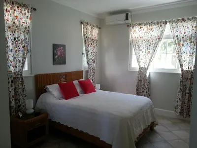 a bedroom with a bed and two windows with red pillows at Los Balcones in Sosúa