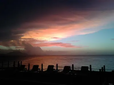 a sunset on the beach with chairs and the ocean at Los Balcones in Sosúa