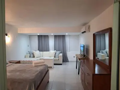 a hotel room with a bed and a couch at Modern condo in middle of Sosua in Sosúa