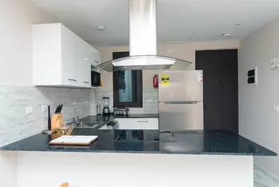 a kitchen with a black counter top and a refrigerator at Cana Rock Star D208 Jaccuzi Pool Golf and Private Beach in Punta Cana