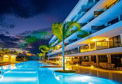 a hotel swimming pool with a palm tree in front of a building at Cana Rock Star D208 Jaccuzi Pool Golf and Private Beach in Punta Cana