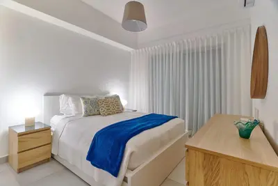 a white bedroom with a bed and a wooden table at Juan Dolio RD Beach Retreat in Juan Dolio