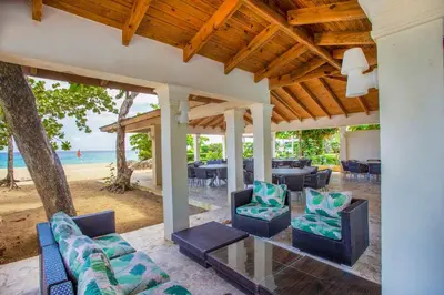 an outdoor patio with chairs and tables on the beach at Rheia Properties - SANTA FE in Sosúa
