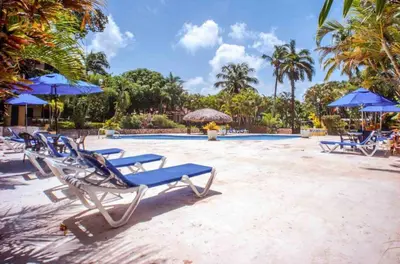 a group of lounge chairs and umbrellas on a beach at nNomad Apartment steps to Sirena - Apartment in Sosúa