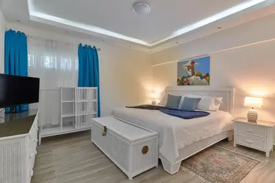 a white bedroom with a bed and a flat screen tv at Costa Del Sol Juan Dolio 2BR Sunset, Beach Front in Juan Dolio