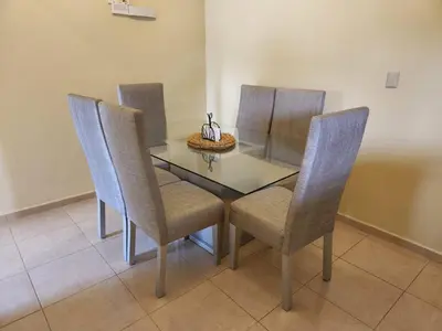 a dining room table with three chairs and a glass top at Remanso 1 in Jarabacoa