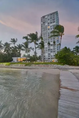 a beach with a tall building and palm trees at Luxurious Caribbean Aquarella 10th in La Puntica de Juan Dolio