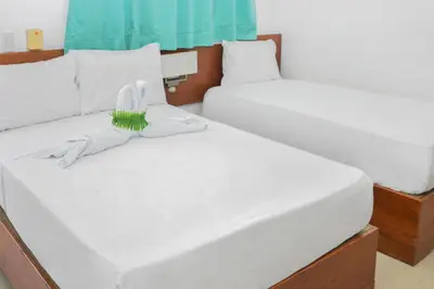 a bedroom with two beds with white sheets at Hotel Restaurant Chino in Santa Bárbara de Samaná