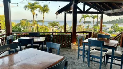 a restaurant with tables and chairs and a view of the ocean at Hotel Restaurant Chino in Santa Bárbara de Samaná