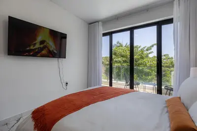 a bedroom with a bed and a tv on a wall at Perla 8- Exclusiva Moderna Villa 4 Habitaciones y Piscina in Sosúa