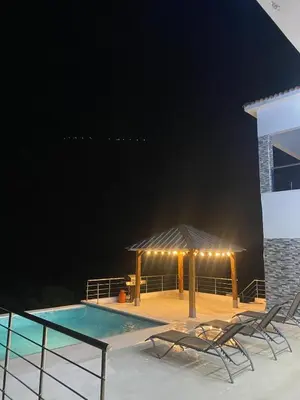 a pool with two chairs and a gazebo at night at Lujosa Villa in Río San Juan J in Río San Juan