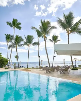 a swimming pool with palm trees and the ocean at Aquarella Deluxe Caribbean Paradise in La Puntica de Juan Dolio
