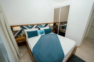 a bedroom with a bed with blue pillows at Apartamento moderno en Cana Rock - Punta Cana in Punta Cana