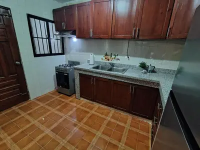 a kitchen with wooden cabinets and a sink and a stove at Céntrico y acogedor apartartamento con Wifi y Parqueo gratis in Santo Domingo