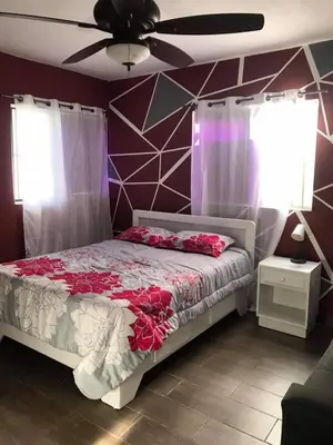 a bedroom with a bed with red flowers on it at Apartment 150m from the beach with pool in Boca Chica