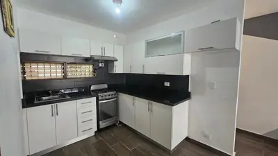 a kitchen with white cabinets and black counter tops at Apartment 150m from the beach with pool in Boca Chica
