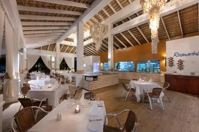 a restaurant with white tables and chairs and chandeliers at Viva Heavens by Wyndham, A Trademark All Inclusive in San Felipe de Puerto Plata