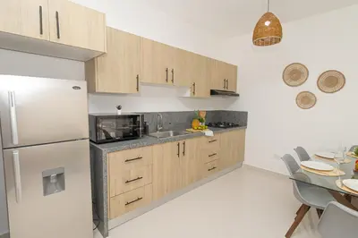 a kitchen with wooden cabinets and a white refrigerator at Cozy 1-BR Apartment in Sunshine Bayahibe in San Rafael del Yuma