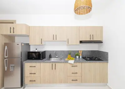 a kitchen with wooden cabinets and a stainless steel refrigerator at Cozy 1-BR Apartment in Sunshine Bayahibe in San Rafael del Yuma