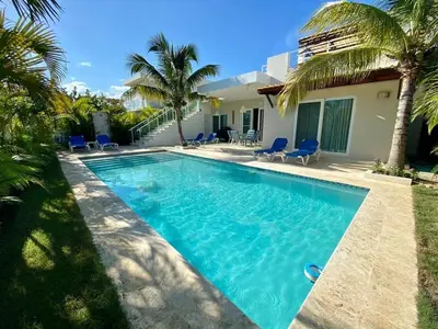 a swimming pool in front of a house with palm trees at Villa Serenity In The Sun in Sosúa