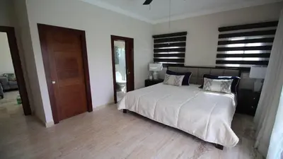 a bedroom with a white bed and a wooden floor at Villa Serenity In The Sun in Sosúa
