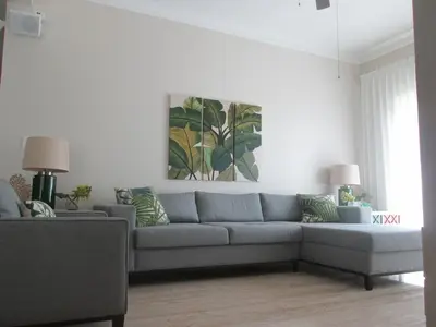 a living room with a gray couch and a painting at Villa Serenity In The Sun in Sosúa