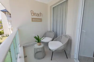 a balcony with two chairs and a plant on it at The beach, my happy place- One bedroom Apartment in Puerto Plata