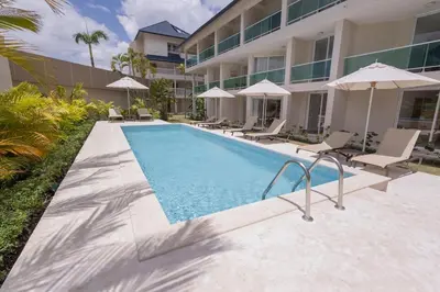 a swimming pool with chairs and umbrellas next to a building at The beach, my happy place- One bedroom Apartment in Puerto Plata