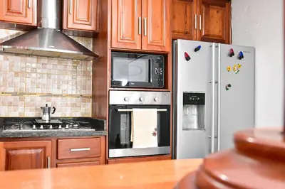 a kitchen with stainless steel appliances and wooden cabinets at Yolanda's house in Bayaguana