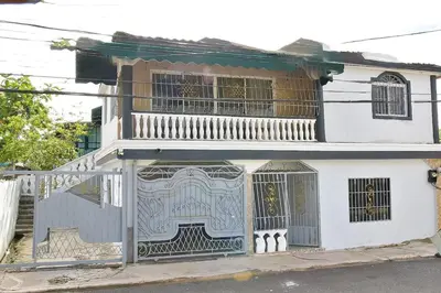 a white house with a gate and a balcony at Yolanda's house in Bayaguana