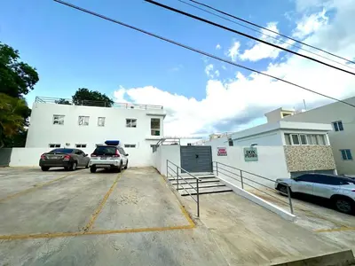 a parking lot with two cars parked in front of a building at Apartamento en La Romana buena vista norte Jacuzzi in La Romana