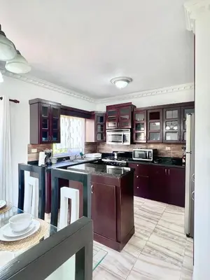 a large kitchen with wooden cabinets and a table at Beautiful and confortable apt in Puerto Plata