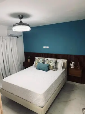 a bedroom with a large bed with a blue wall at Experience Coconut Paradise Apart O2 in San Cristóbal
