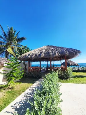 a restaurant with a straw hut on the beach at Serendipia Hotel Nizao in Nizao