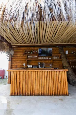 a wooden bar in a resort with a straw roof at Serendipia Hotel Nizao in Nizao