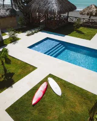 two surfboards sitting on the grass near a swimming pool at Serendipia Hotel Nizao in Nizao